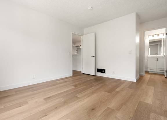 A room with wooden flooring and white walls.