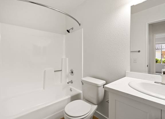 A white bathroom with a toilet, sink, and bathtub.