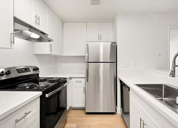 A modern kitchen with a stainless steel refrigerator and black countertops.