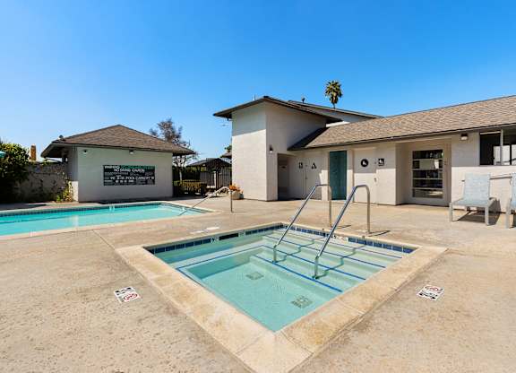 A pool with a diving board in front of a house.