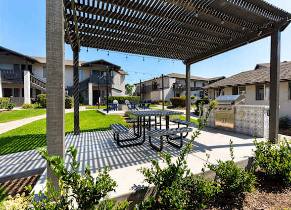 A patio with a table and chairs under a pergola.