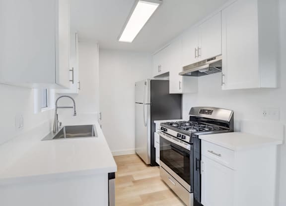 A modern kitchen with white cabinets and stainless steel appliances.