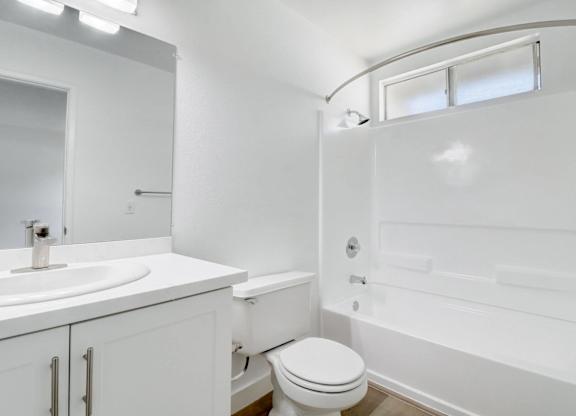 A white bathroom with a toilet, sink, and bathtub.