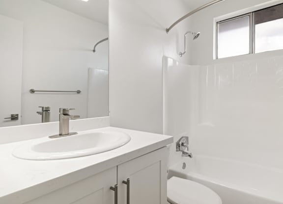 A white bathroom with a sink, toilet, and bathtub.