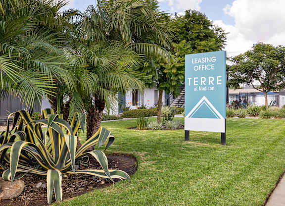 A sign for the Leasing Office at Terra Madison stands in a green lawn.