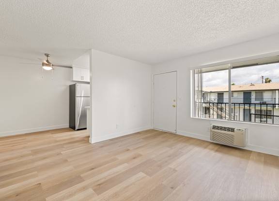 A spacious room with wooden flooring and a large window.