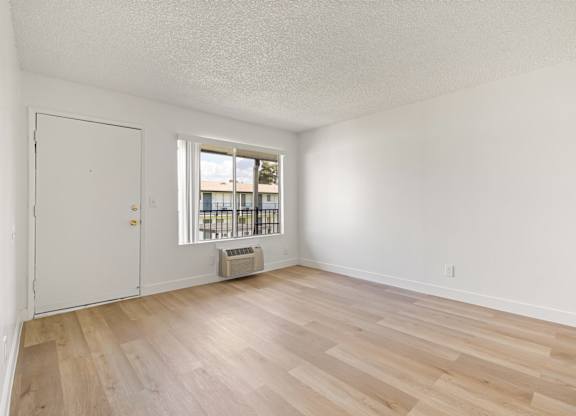 A room with a white door and a window with a view of a building outside.