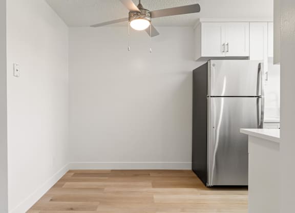 A kitchen with a refrigerator and a ceiling fan.