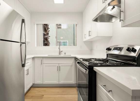 A modern kitchen with white cabinets and stainless steel appliances.