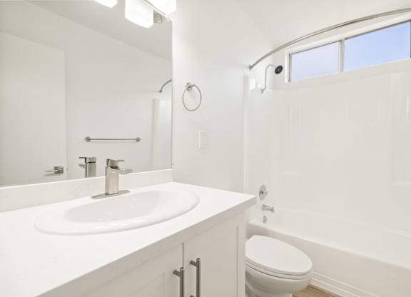 A white bathroom with a sink, toilet and tub.