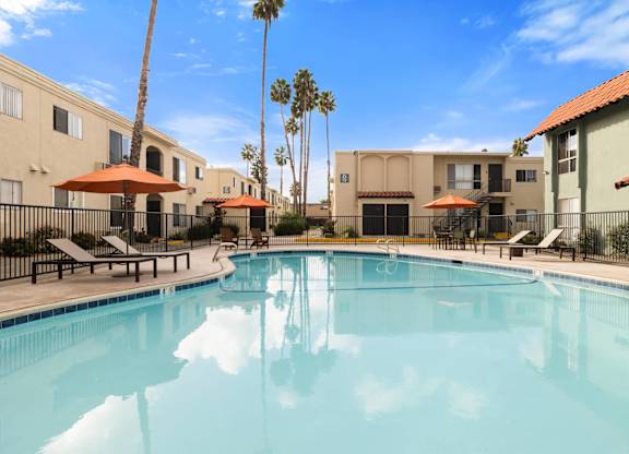 A swimming pool surrounded by palm trees and buildings.