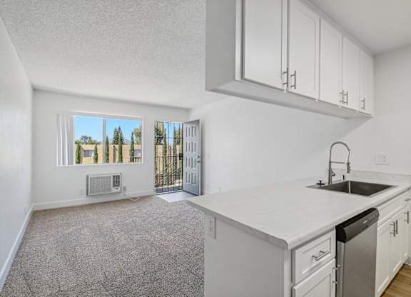 A kitchen with white cabinets and a white countertop with a sink and dishwasher.