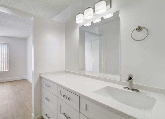 A bathroom with a sink, mirror, and lighting fixture.
