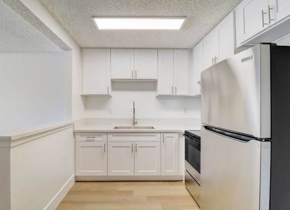 A kitchen with white cabinets and a black refrigerator.
