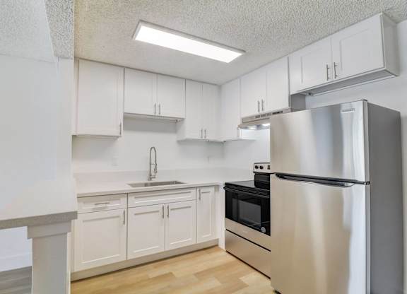 A kitchen with white cabinets and a stainless steel refrigerator.