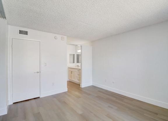 A white room with a wooden floor and a white door.