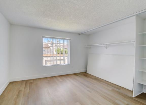 Empty room with a window and wooden flooring.