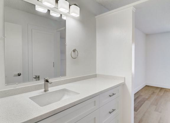 A white bathroom with a sink and mirror.