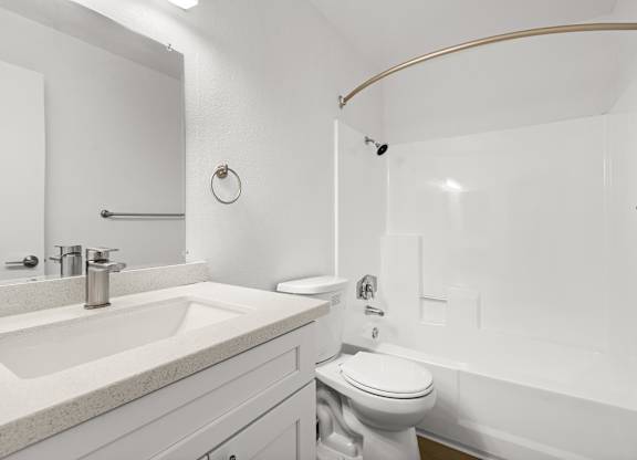 A white bathroom with a toilet, sink, and shower.