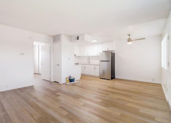 A kitchen with white walls and wooden floors.