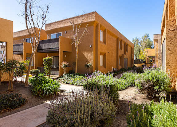 A building with a yellow exterior and a garden in front.