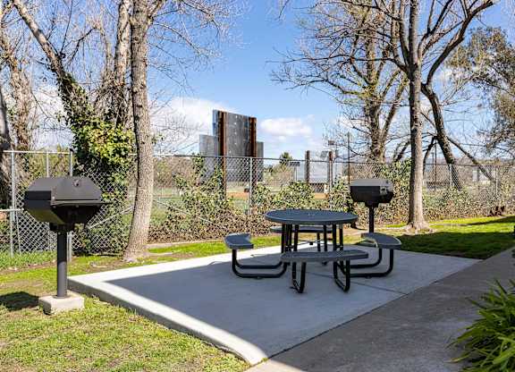 A picnic table is surrounded by a chain link fence.