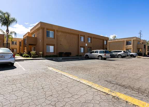 A parking lot with a building in the background and a car parked in the lot.