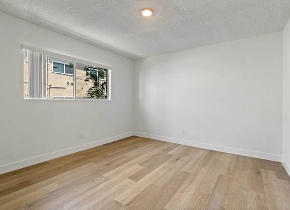 A room with a window and wooden flooring.