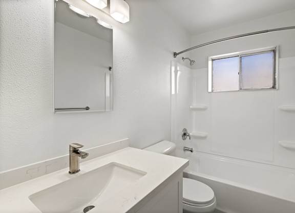 A white bathroom with a sink, toilet, and bathtub.