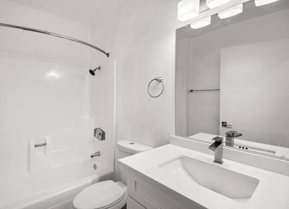 A white bathroom with a toilet, sink, and mirror.