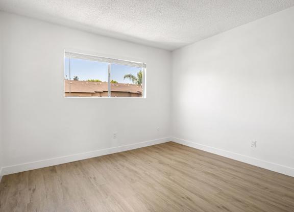 A room with a window showing a view of a building outside.