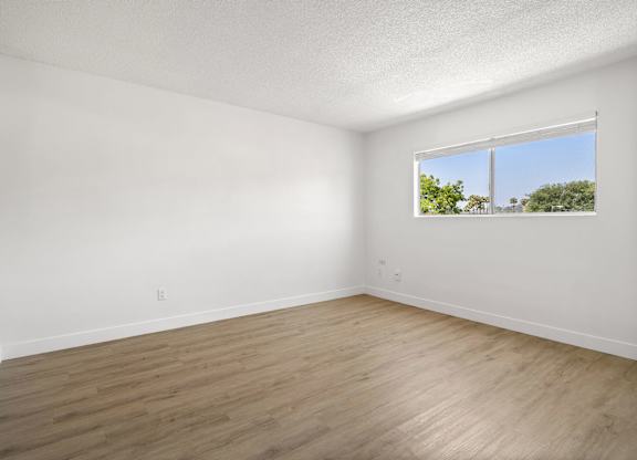 Empty room with a window and wooden floor.