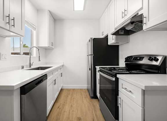 A modern kitchen with white cabinets and stainless steel appliances.