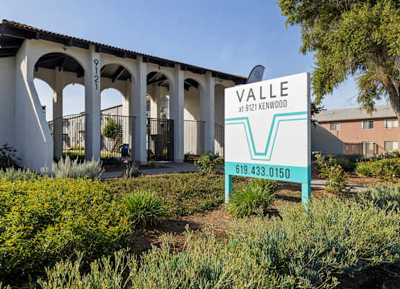 A sign for Valle at 9121 Kenwood stands in front of a building.