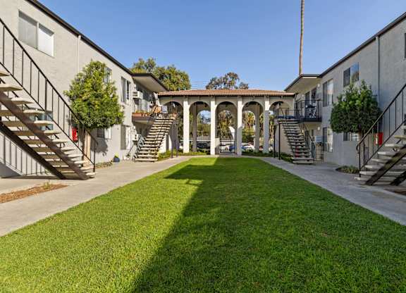 A courtyard with a grassy area and a building on either side.