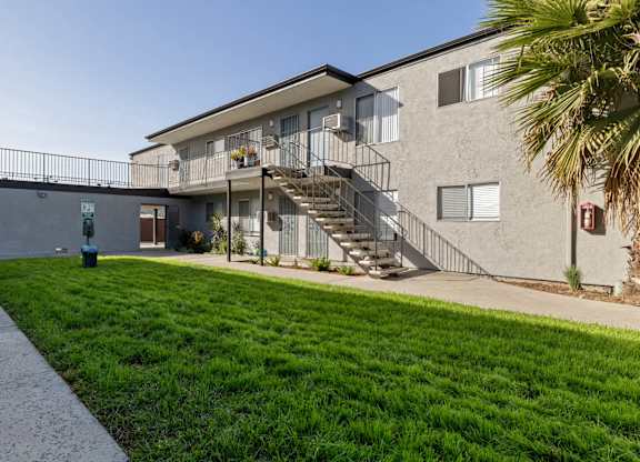 A building with a staircase and a green lawn in front.