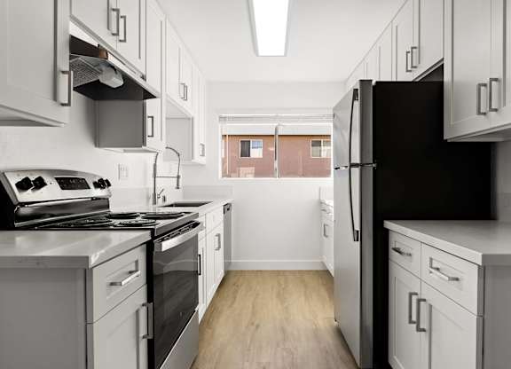 A kitchen with white cabinets and a black refrigerator.