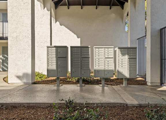 A row of mailboxes are lined up on a sidewalk.