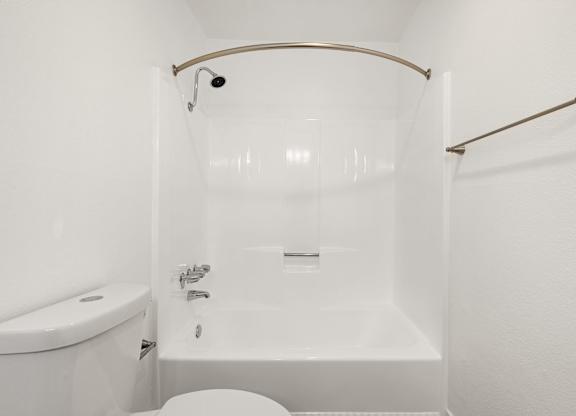 A white bathroom with a tub, toilet and sink.