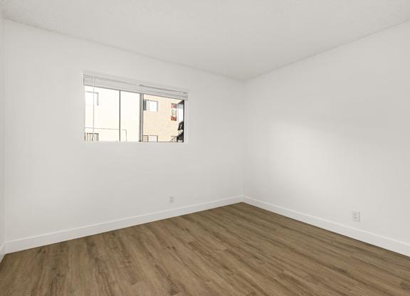 Empty room with a window and wooden floor.