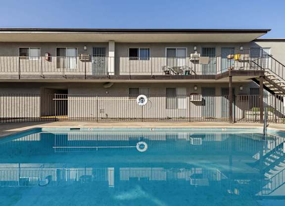 A pool in front of a building with a staircase on the right side.