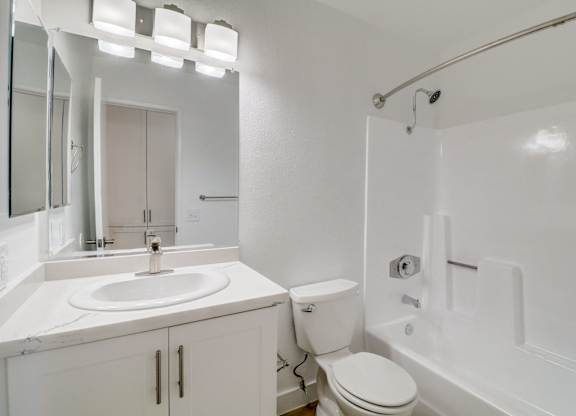 A white bathroom with a sink, toilet, and bathtub.