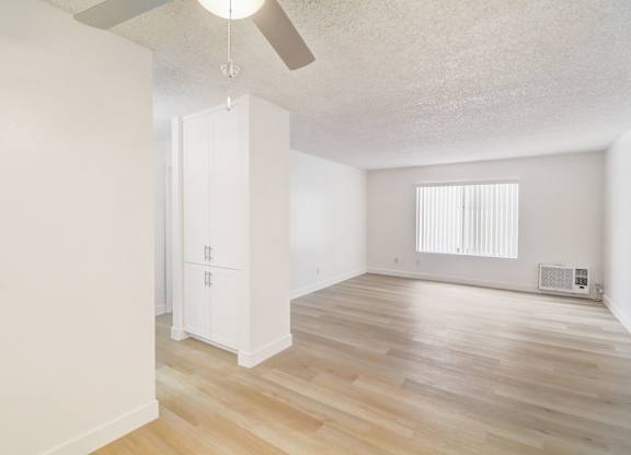 A room with a ceiling fan and a window with blinds.