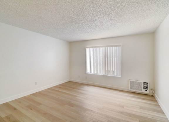 A room with wooden floors and a window with blinds.