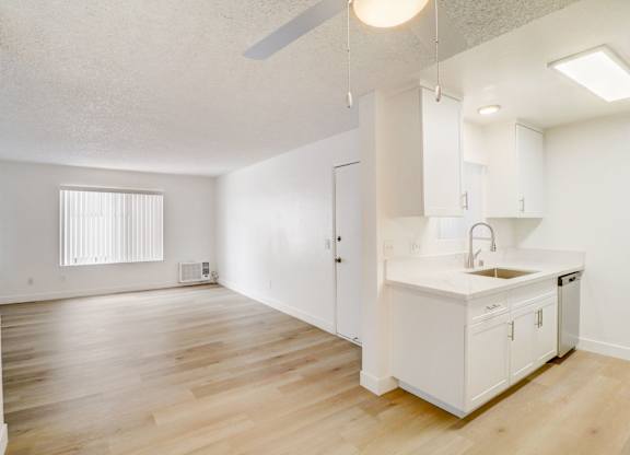 A kitchen with white cabinets and a wooden floor.