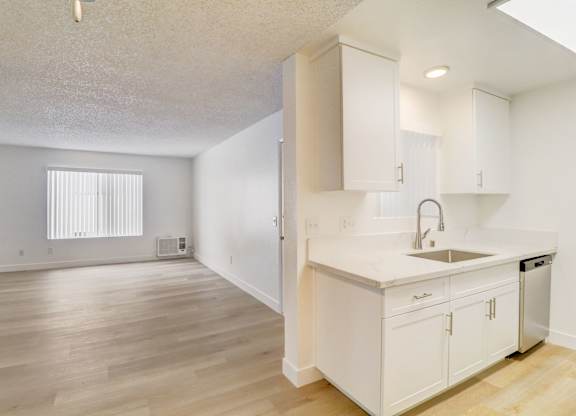 A kitchen with white cabinets and a wooden floor.