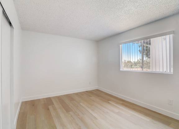 A room with a window and wooden flooring.