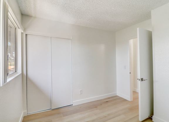 A room with a white door and a window on the left.