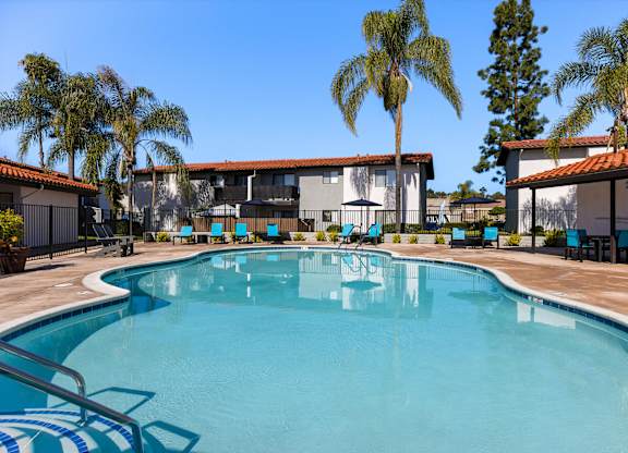A swimming pool surrounded by palm trees and a building.