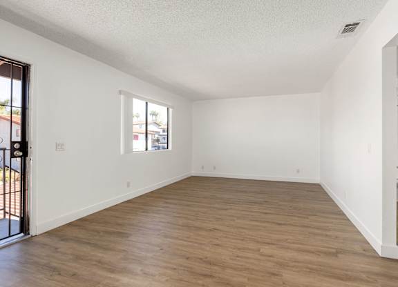 Empty room with wooden flooring and white walls.